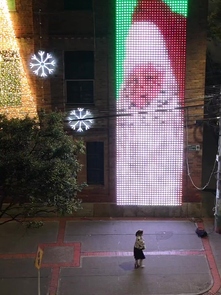 Sección vertical de pantalla LED que cubre tres pisos, con una persona caminando por el andén al pie